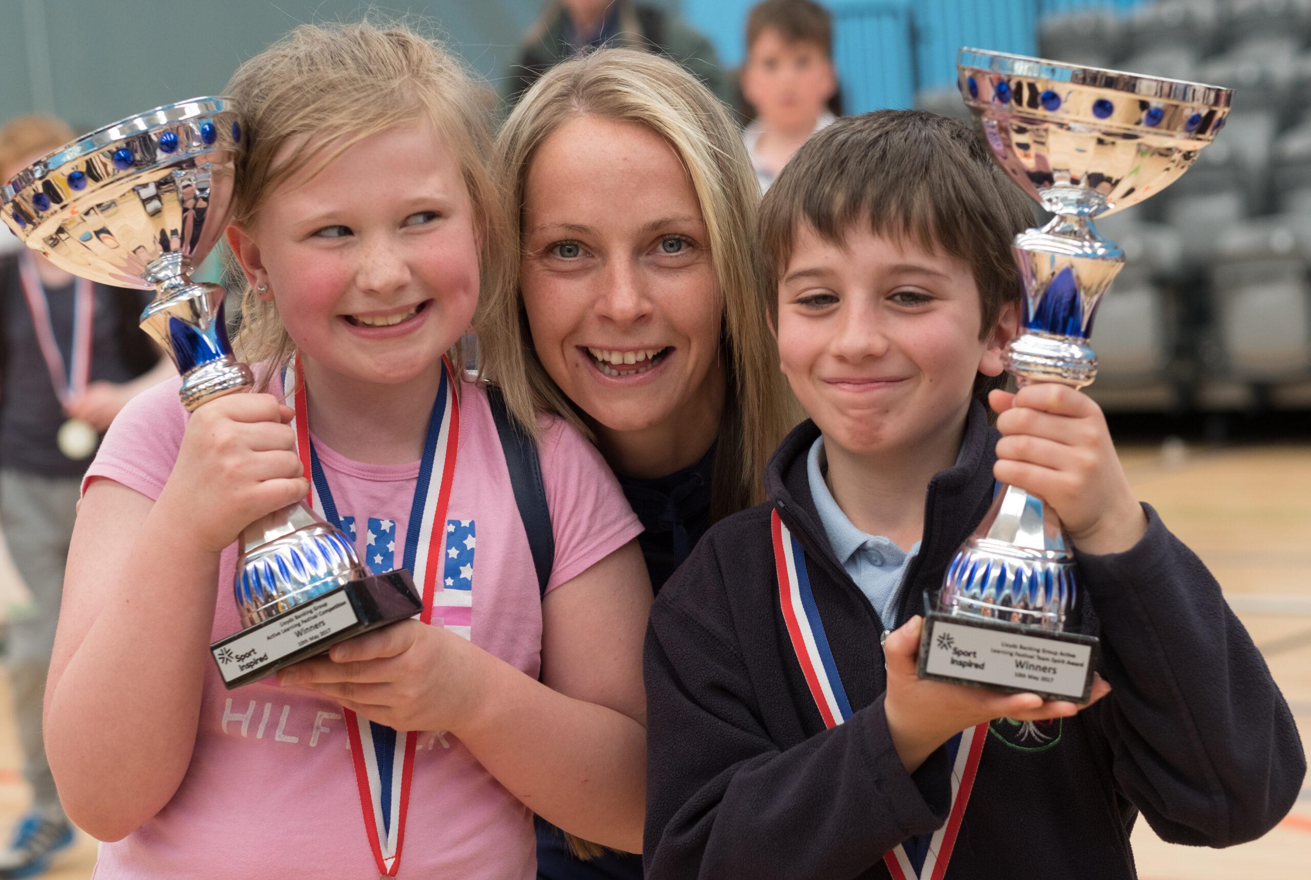 Women poses with two children holding a winning cup.